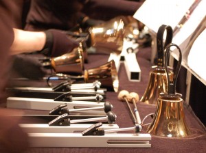 A photo of handbells and chimes on a long table