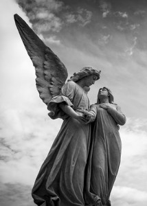 A cemetery statue of an angel leading a soul to heaven